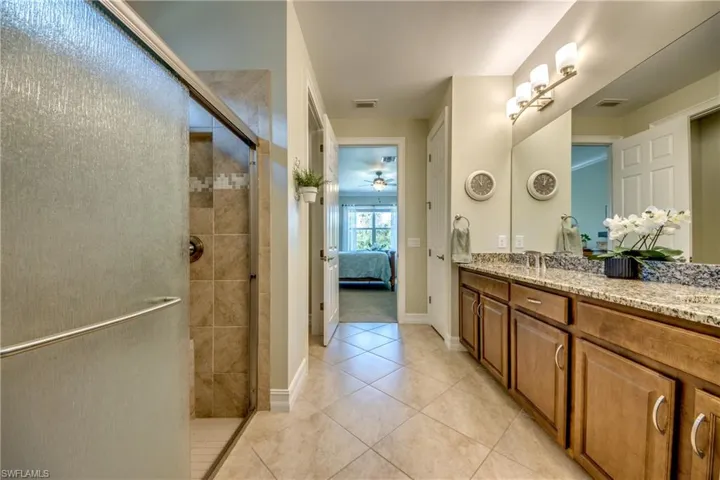 Bathroom with tile floors, a shower with shower door, and vanity