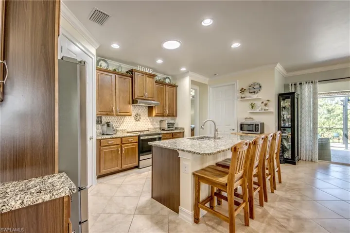 Kitchen with tasteful backsplash, a kitchen island with sink, a breakfast bar area, appliances with stainless steel finishes, and sink