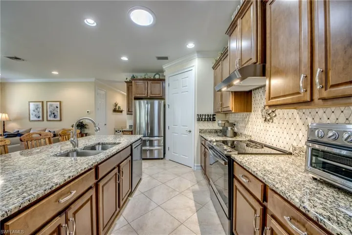 Kitchen featuring stainless steel appliances, light stone counters, sink, tasteful backsplash, and light tile floors