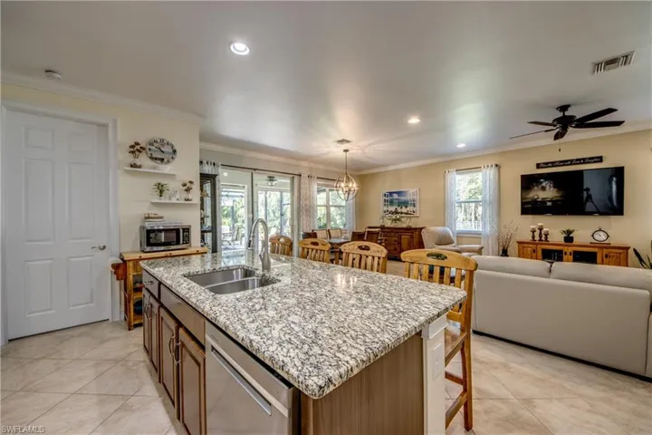 Kitchen with ceiling fan, stainless steel appliances, pendant lighting, sink, and a kitchen island with sink