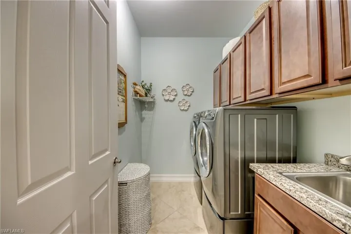 Laundry room with sink, washer and dryer, light tile flooring, and cabinets