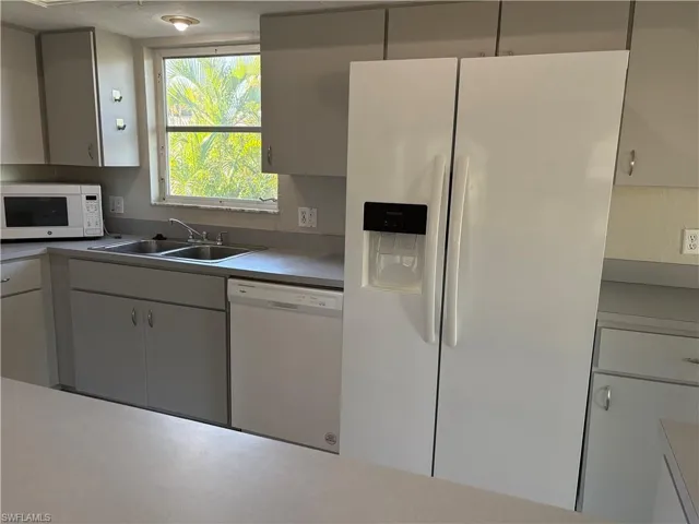 Kitchen with white appliances, light countertops, and white cabinets