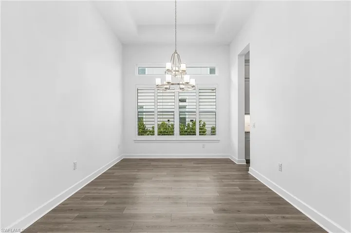 Unfurnished dining area featuring a chandelier and wood finished floors