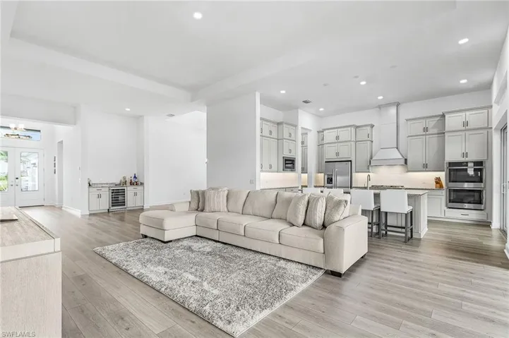 Living room with recessed lighting, light wood-type flooring, wine cooler, french doors, and a chandelier