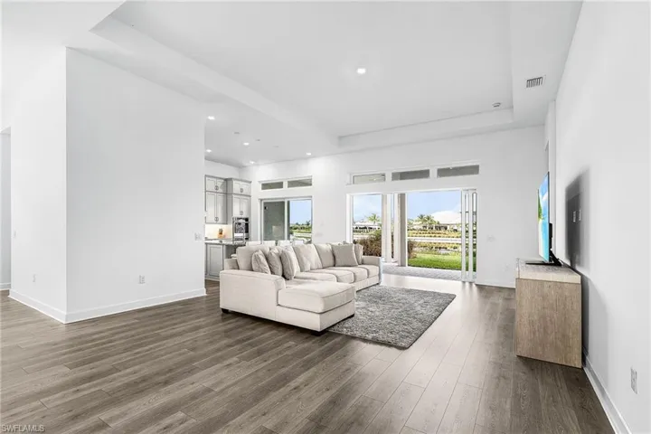 Living room featuring a raised ceiling, recessed lighting, dark wood finished floors, and a high ceiling