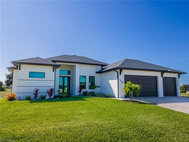 Prairie-style house with a front yard, driveway, an attached garage, and stucco siding