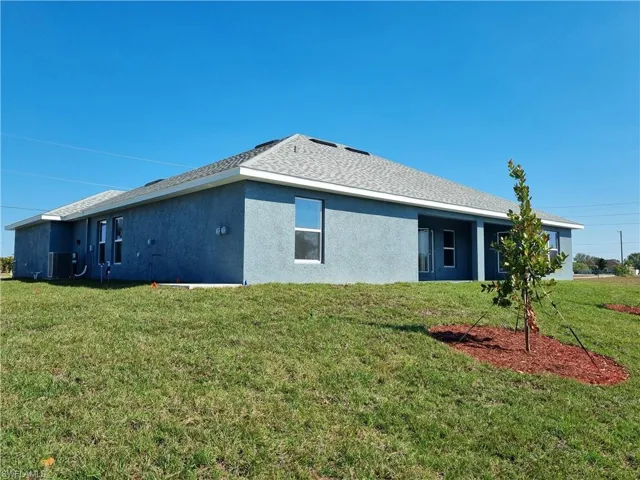 Rear view of house with central AC and a lawn