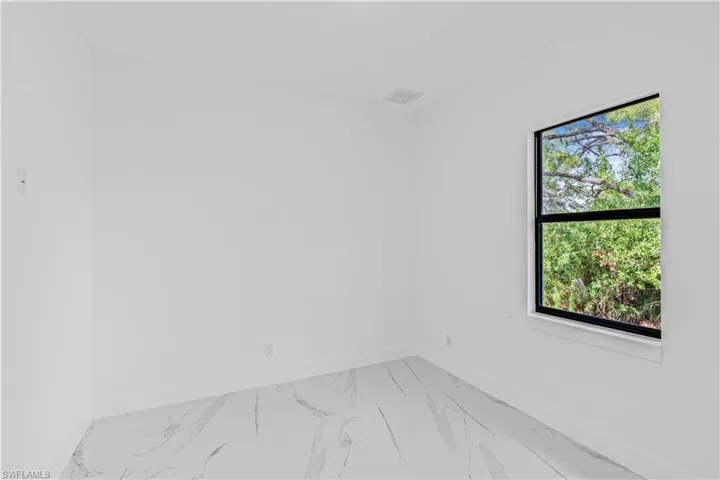 Empty room featuring light marble finish flooring and baseboards