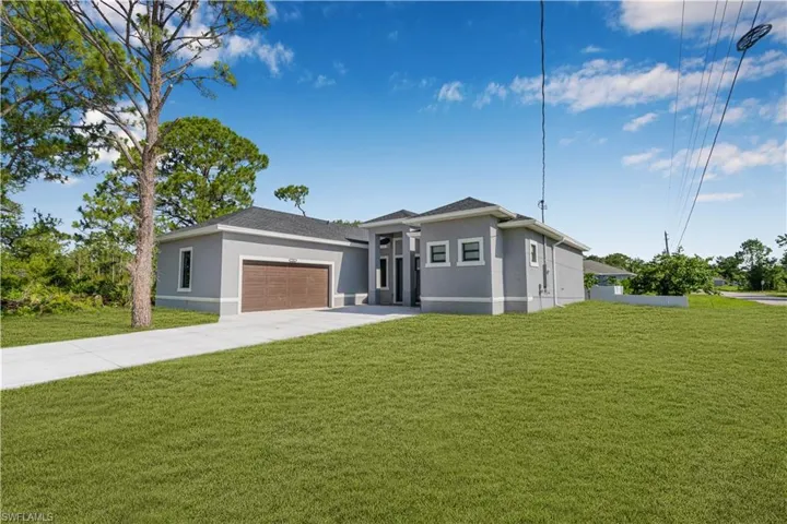 Prairie-style house featuring stucco siding, a front lawn, an attached garage, and driveway