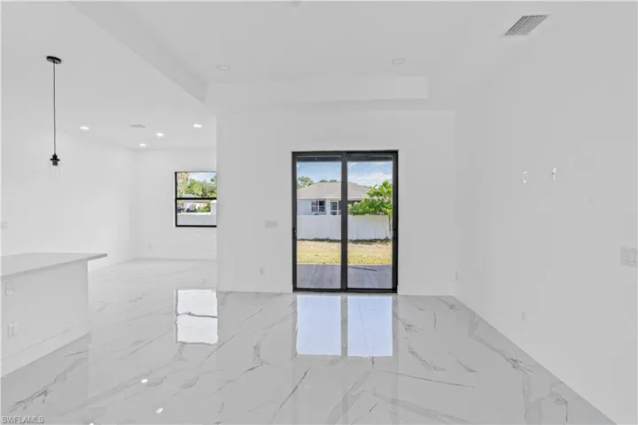Spare room featuring healthy amount of natural light, a tray ceiling, light marble finish floors, and recessed lighting