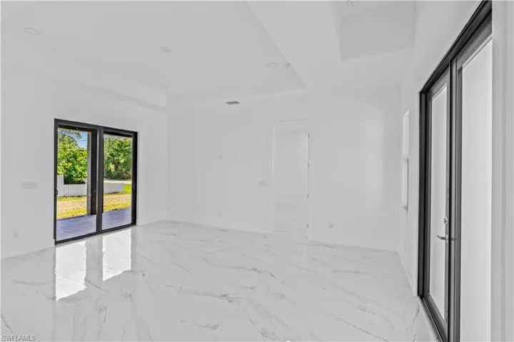 Spare room with a tray ceiling and light marble finish floors