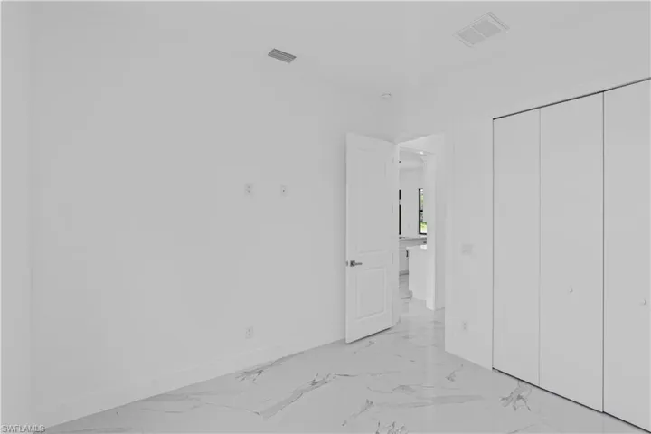 Unfurnished bedroom featuring light marble finish flooring and a closet