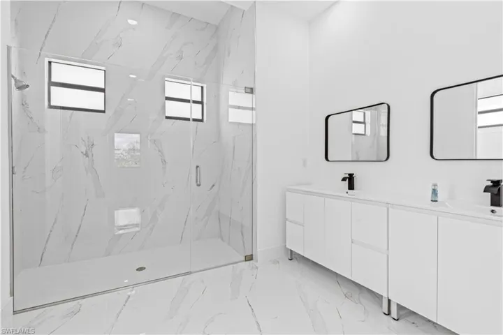 Full bathroom featuring double vanity and a marble finish shower