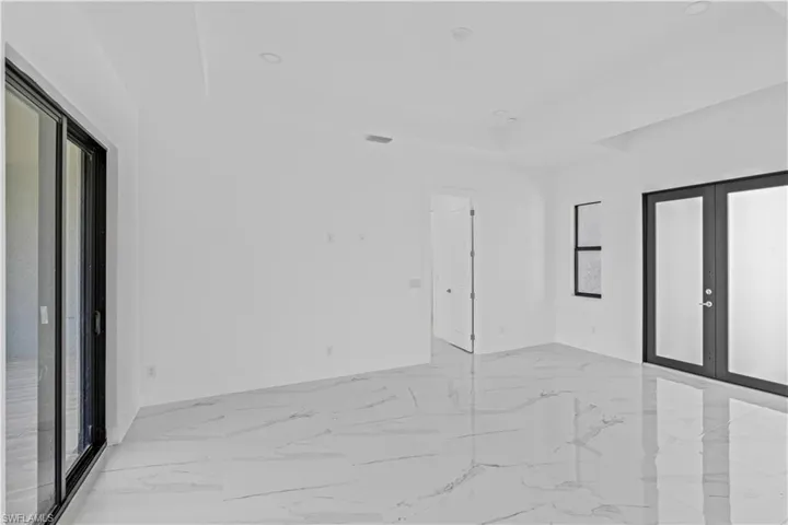 Spare room with french doors, a tray ceiling, light marble finish floors, and recessed lighting