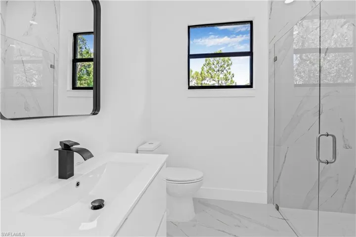 Bathroom featuring a marble finish shower, vanity, and light marble finish floors