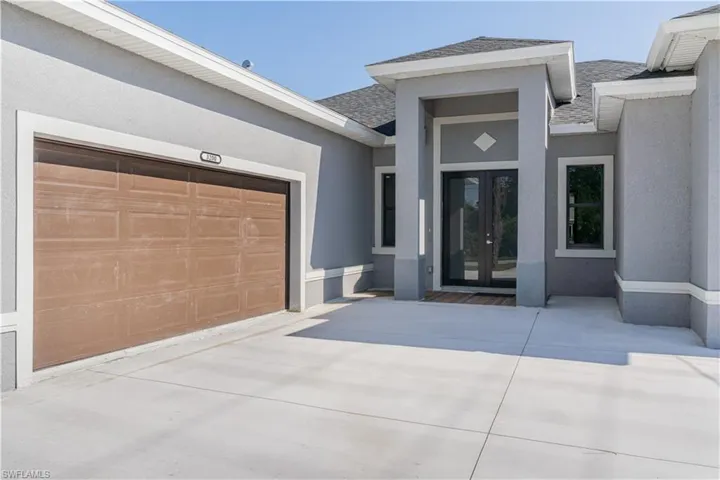 Doorway to property with french doors, a garage, concrete driveway, stucco siding, and roof with shingles