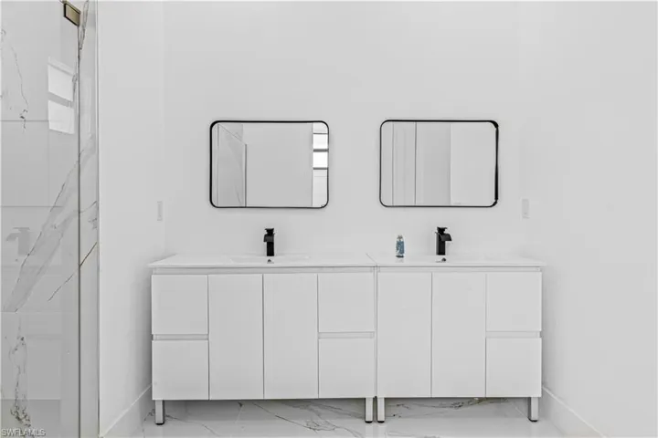 Bathroom featuring double vanity and light marble finish flooring