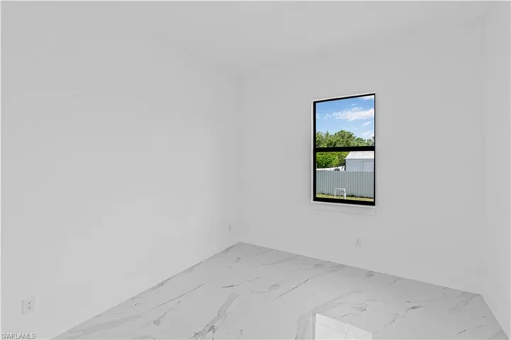 Unfurnished room featuring baseboards and light marble finish flooring