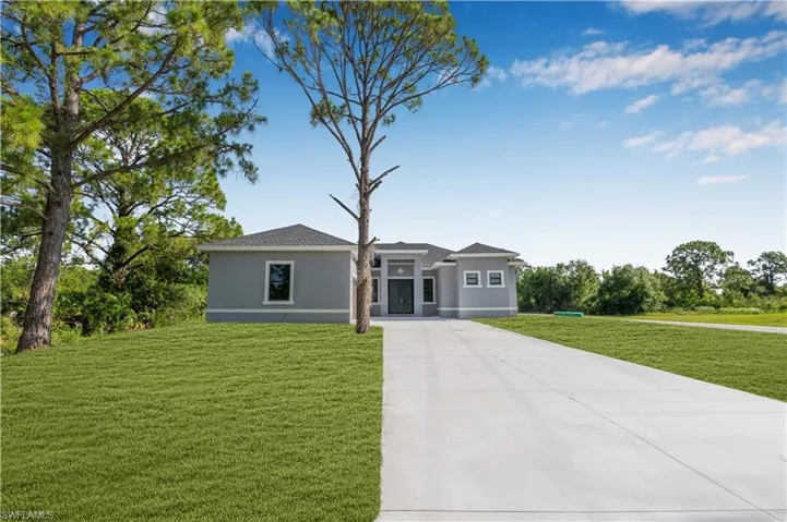 Prairie-style home with concrete driveway, a front yard, and stucco siding