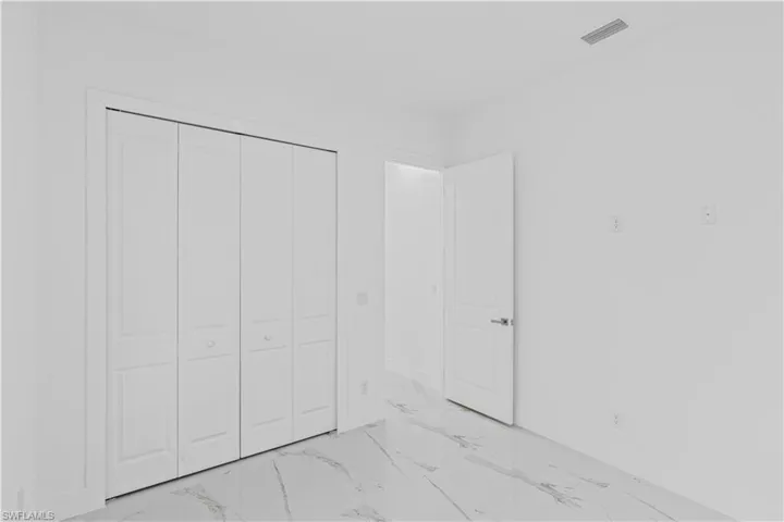 Unfurnished bedroom with a closet and light marble finish flooring