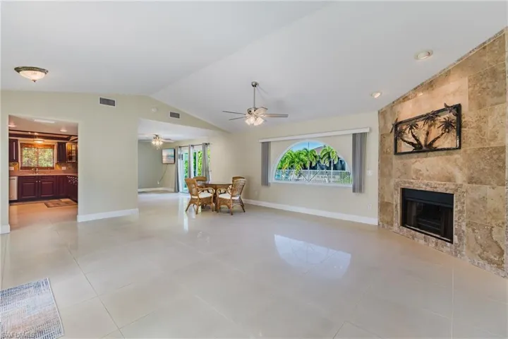Living room with lofted ceiling, plenty of natural light, a tile fireplace, light tile patterned floors, and a ceiling fan
