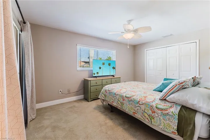 Bedroom with a closet, light carpet, and a ceiling fan