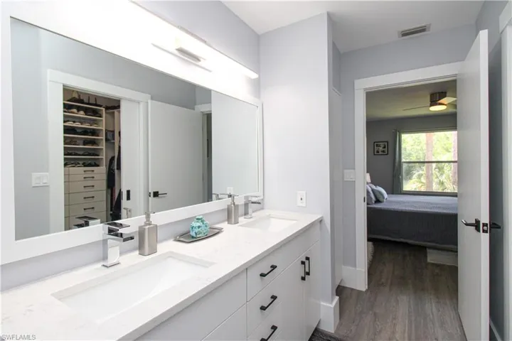 Bathroom featuring ceiling fan, double sink vanity, and wood-type flooring