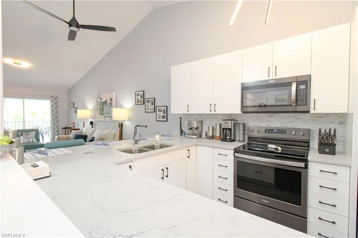 Kitchen featuring sink, tasteful backsplash, white cabinetry, and appliances with stainless steel finishes