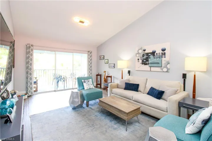 Living room with high vaulted ceiling and hardwood / wood-style floors