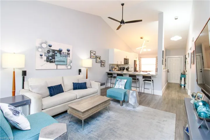 Living room with light hardwood / wood-style floors, high vaulted ceiling, and ceiling fan