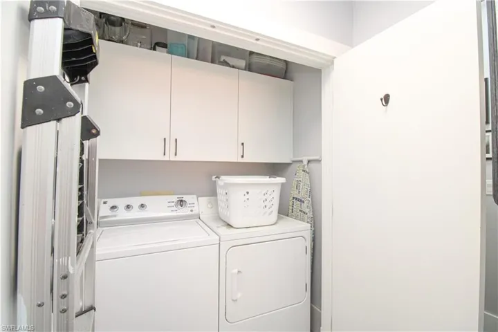 Laundry room with washer and clothes dryer and cabinets