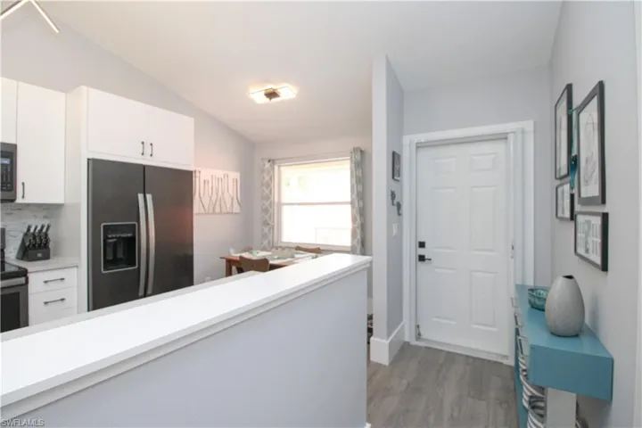 Kitchen featuring lofted ceiling, tasteful backsplash, wood-type flooring, white cabinets, and appliances with stainless steel finishes