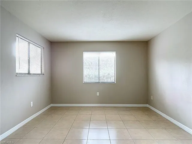 Master bedroom with a healthy amount of sunlight, light tile patterned floors, and a textured ceiling