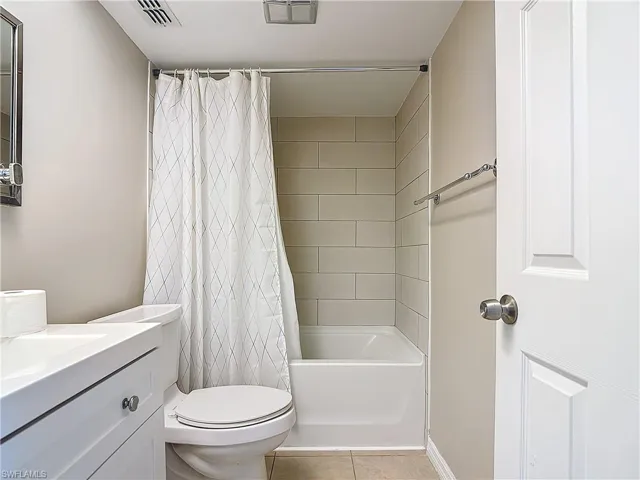Full bathroom with toilet, vanity, tile patterned floors, and shower / bathtub combination with curtain