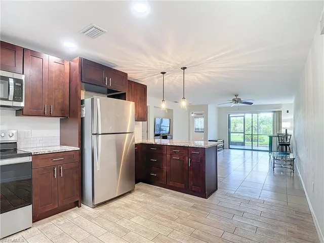 Kitchen featuring kitchen peninsula, appliances with stainless steel finishes, ceiling fan, and light hardwood / wood-style floors