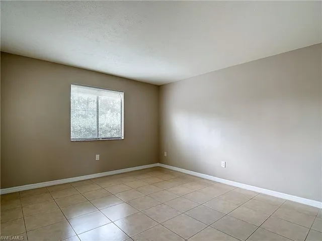 Master bedroom with a textured ceiling and light tile patterned floors
