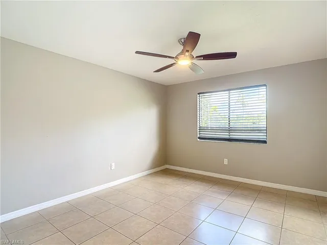 Empty room featuring light tile patterned flooring and ceiling fan
