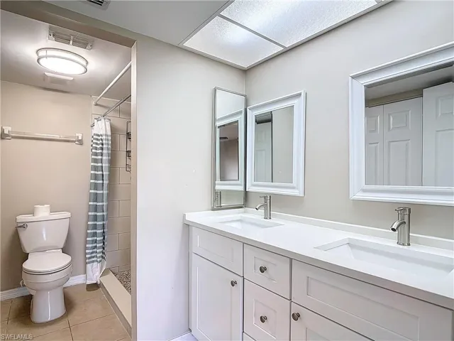 Bathroom featuring vanity, walk in shower, tile patterned floors, and toilet