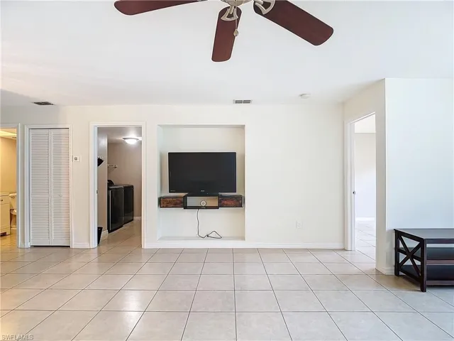 Unfurnished living room featuring ceiling fan, light tile patterned floors, and independent washer and dryer