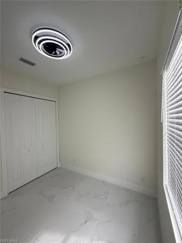 Unfurnished bedroom featuring light marble finish flooring and a closet