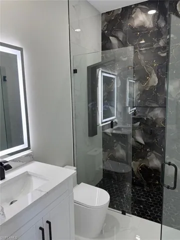 Bathroom featuring a marble finish shower and vanity