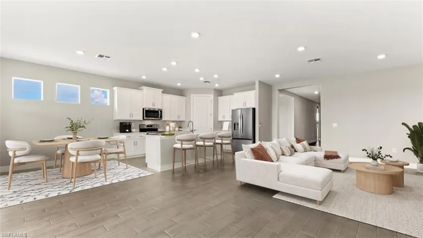 Recessed lighting throughout, wood-finish flooring, white cabinetry, and stainless steel appliances