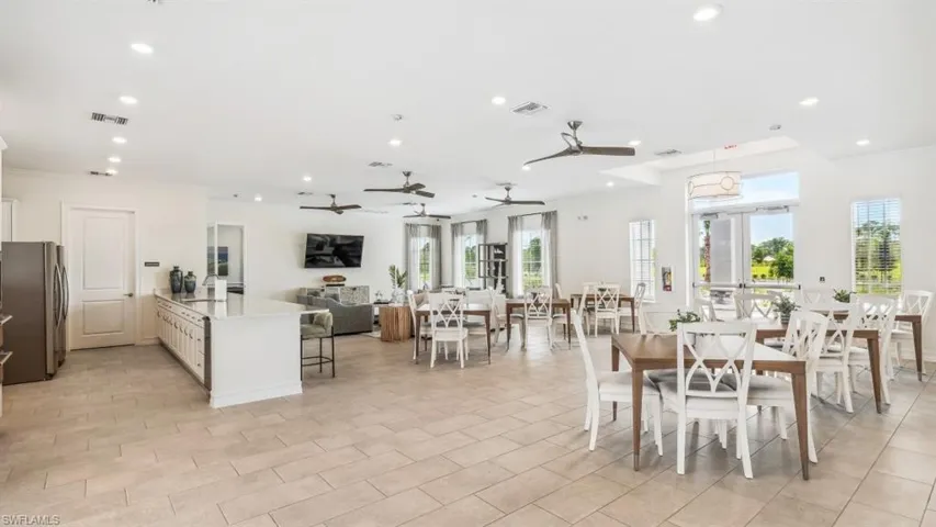 Spacious open-concept interior featuring light-toned tile flooring, recessed lighting, ceiling fans, and an expansive kitchen island with a light-colored countertop