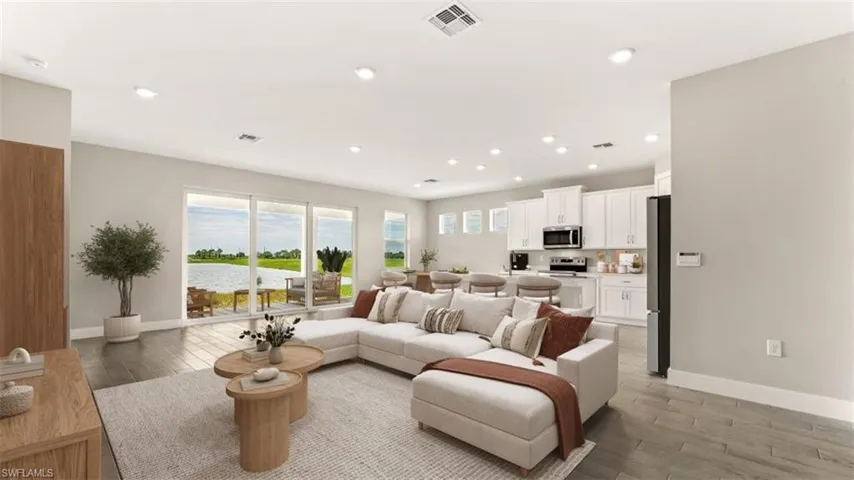 Open concept living space with recessed lighting, wood-finish flooring, and white kitchen cabinetry