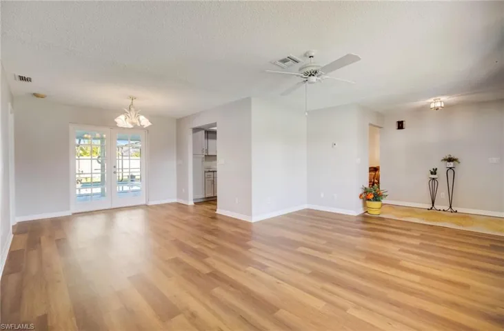 Unfurnished living room featuring ceiling fan with notable chandelier, a textured ceiling, and light hardwood / wood-style floors