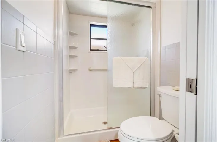 Bathroom with tile walls, toilet, and step-in shower