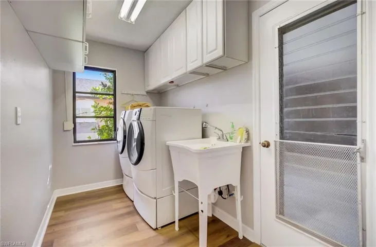 Laundry room featuring independent washer and dryer, light hardwood / wood-style floors, and cabinets