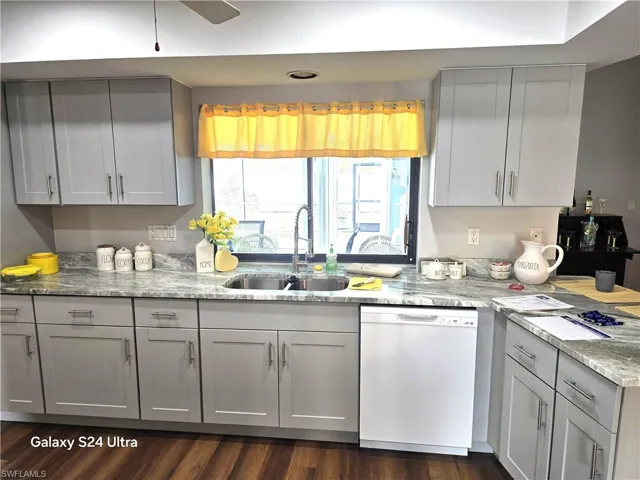 Kitchen with light granite counters, dishwasher, sink, and stunning gray cabinets