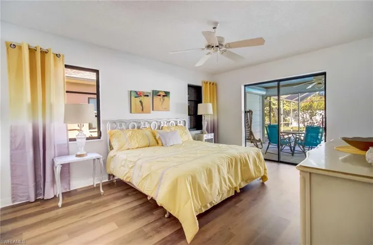 Bedroom with a textured ceiling, access to outside, wood-type flooring, and ceiling fan
