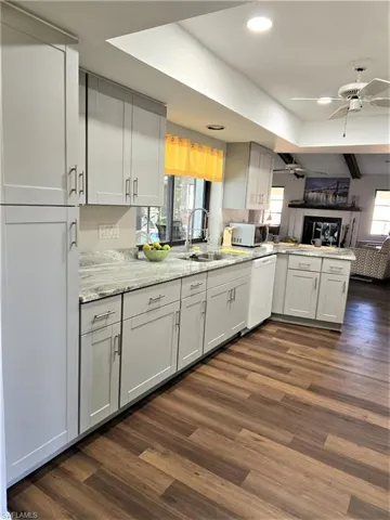 Kitchen with dark wood-look flooring, Built-in Pantry, recessed lighting, ceiling fan, and stainless sink with pot filler faucet!